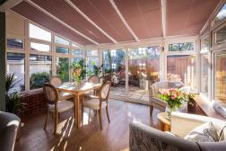 Photo of Parkland conservatory off Coach House with armchairs & dining table overlooking garden