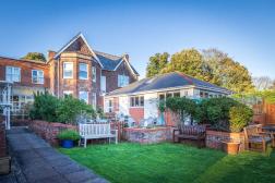 View of Parkland House building from garden with lawn, planting and seating