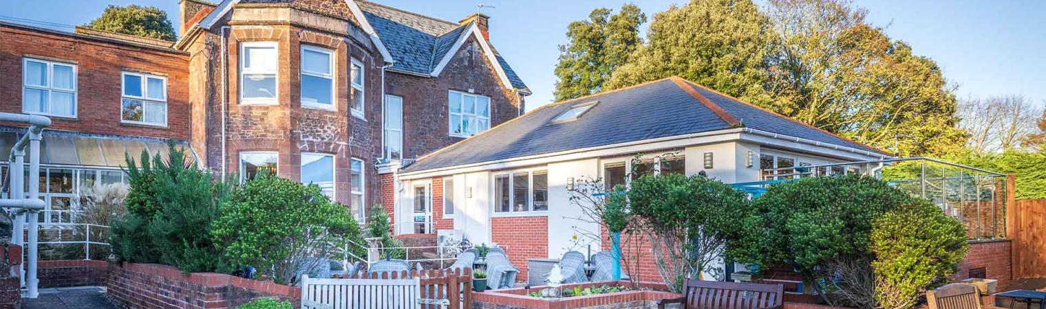 View of Parkland House building from garden with lawn, planting and seating