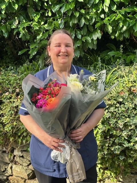 Showing Vicky standing in garden with mixed bouquets of flowers