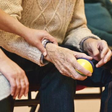Staff helping an elderly person with a ball